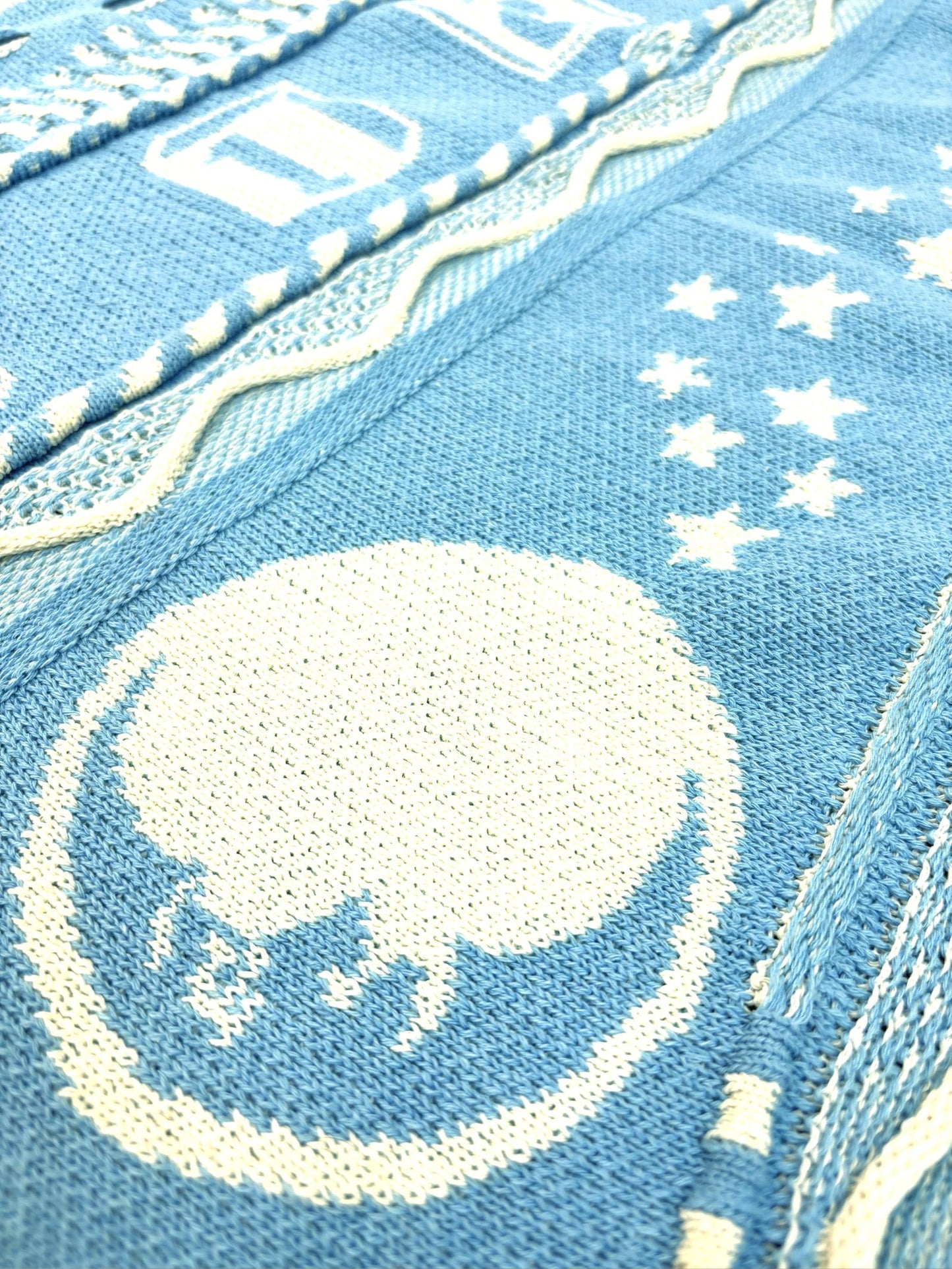 Close-up of a blue fabric with white embroidery featuring a bear design.