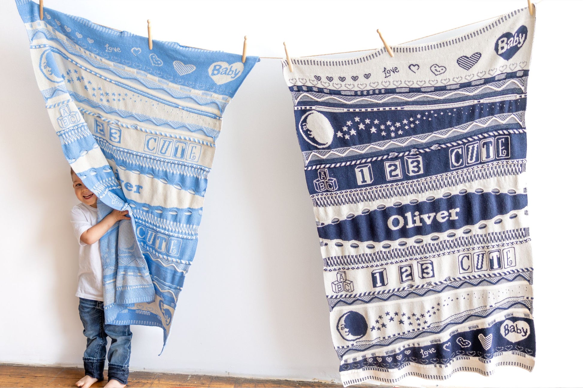 Two baby blankets with patterns and text, one held by a child, on a white background.