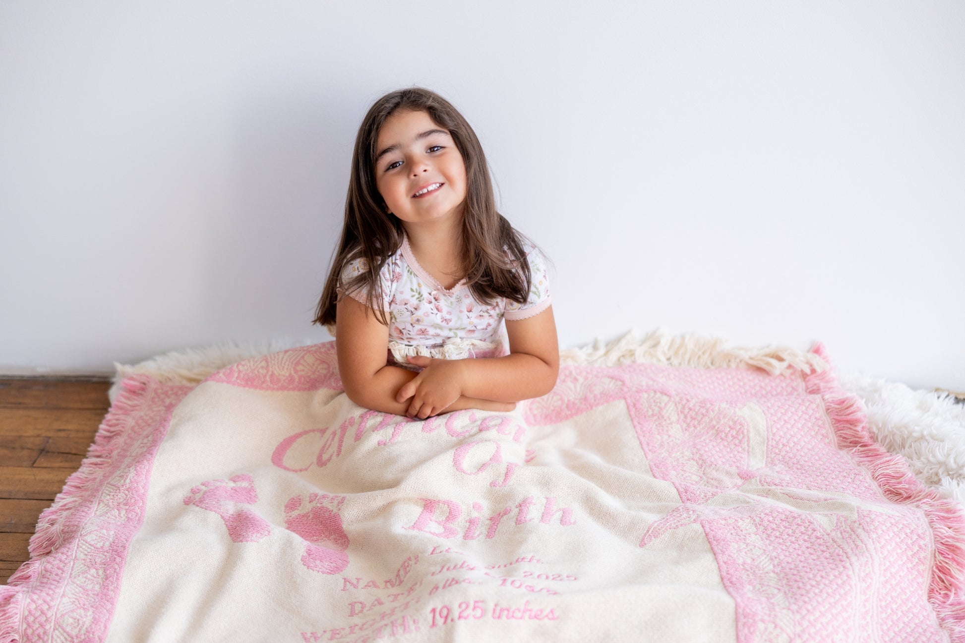 Young girl sitting on a pink and white blanket with text