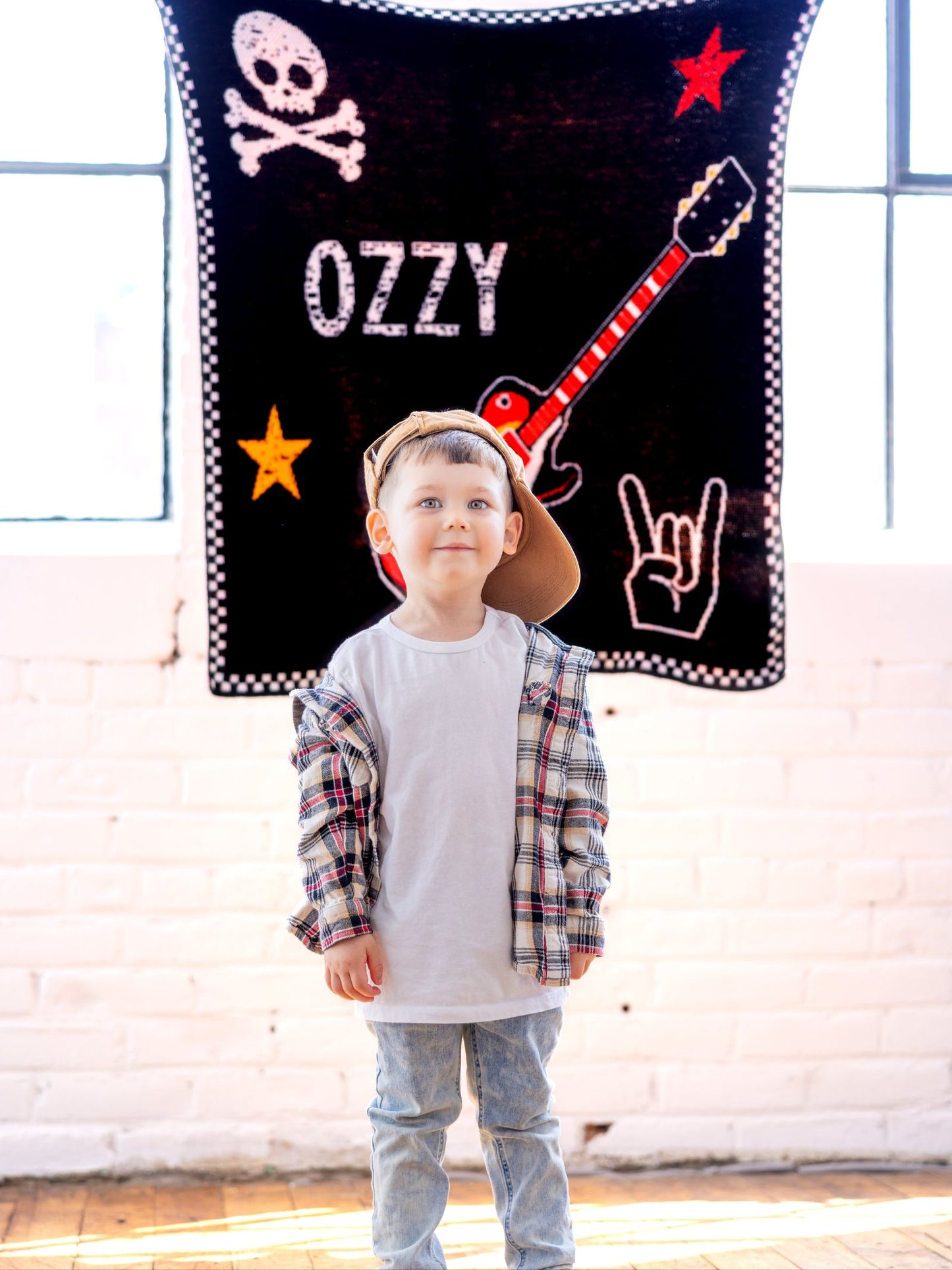 Child standing in front of a decorative wall with 'Ozzy' and rock-themed elements.